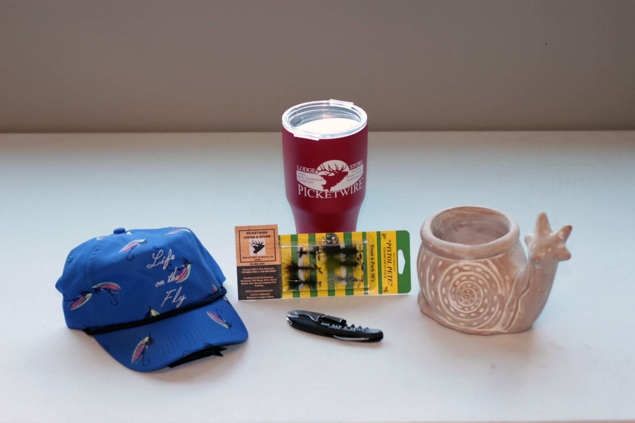 Life on the fly hat, travel tumbler, Pistol Pete lures, bottle opener and snail planter from Picketwire Lodge & Store, 7600 CO-12, Weston, CO.